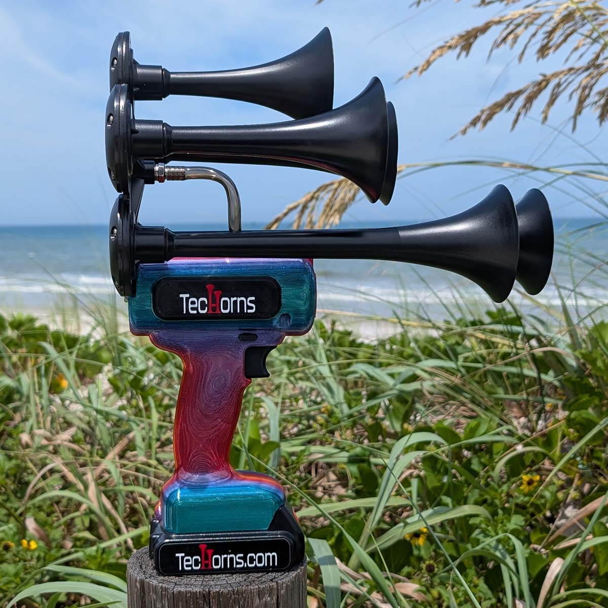 TecHorns Fire & Ice Candy 5-Horn – 130 dB handheld train horn with 20 V lithium battery, shown outdoors near beach dunes and ocean surf for a bold lifestyle look