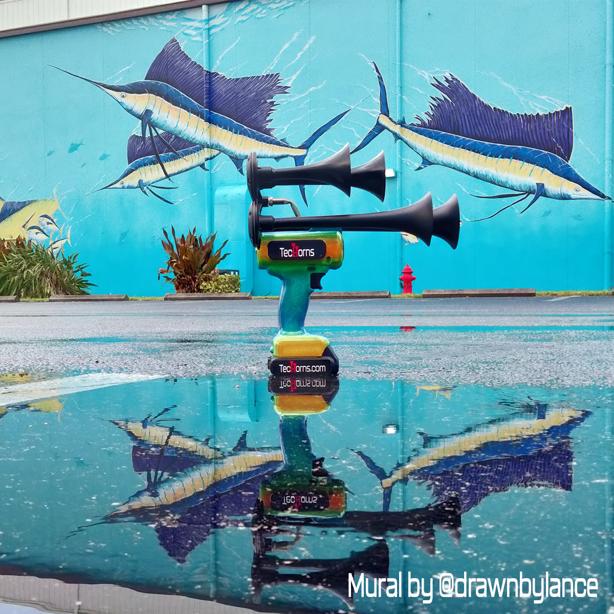 TecHorns Mango Bay Candy 4-Horn – handheld train horn with 20 V lithium battery, captured with a sea life mural backdrop and vivid reflection photography that enhances its tropical candy color fade