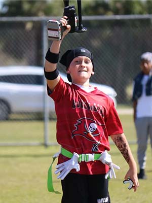 Teen celebrating at a flag football game holding a black TecHorn 2-Horn handheld train horn with 20 V lithium battery, capturing the excitement and fun energy of game day