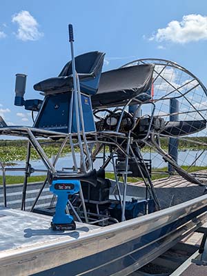Blue TecHorn 2-Horn handheld train horn with 20 V lithium battery displayed on an airboat at the dock, highlighting marine adventure style and powerful Florida craftsmanship