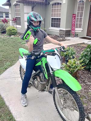 Green TecHorn 2-Horn handheld train horn with 20 V lithium battery held by a rider on a matching green dirt bike, showcasing custom color coordination and outdoor fun