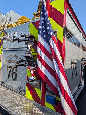 'Merica and Thin RED Line TecHorn 4-Horn handheld train horns with 20 V lithium batteries mounted on a fire truck beside an American flag, symbolizing pride, service, and American craftsmanship