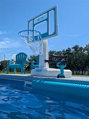 Teal TecHorn 4-Horn handheld train horn with 20 V lithium battery sitting poolside beside a basketball hoop under a clear blue sky, showcasing summer fun and sporty style
