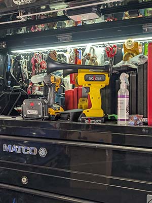 Yellow TecHorn 2-Horn handheld train horn with 20 V lithium battery displayed on a metal toolbox, showcasing compact power and rugged workshop performance
