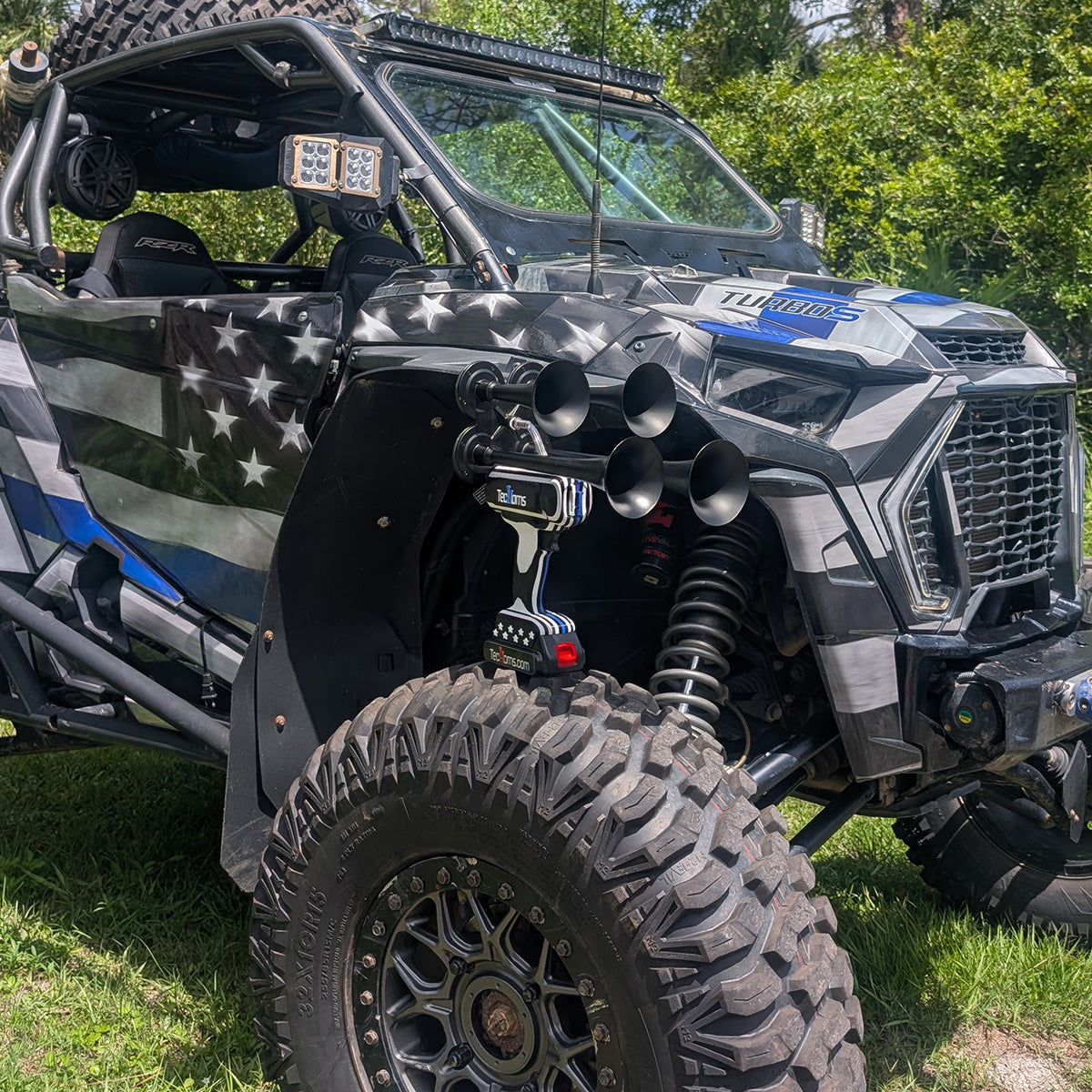 Thin BLUE Line TecHorns 4-Horn – handheld train horn with 20 V lithium battery, displayed on the front tire of a Thin BLUE Line wrapped UTV