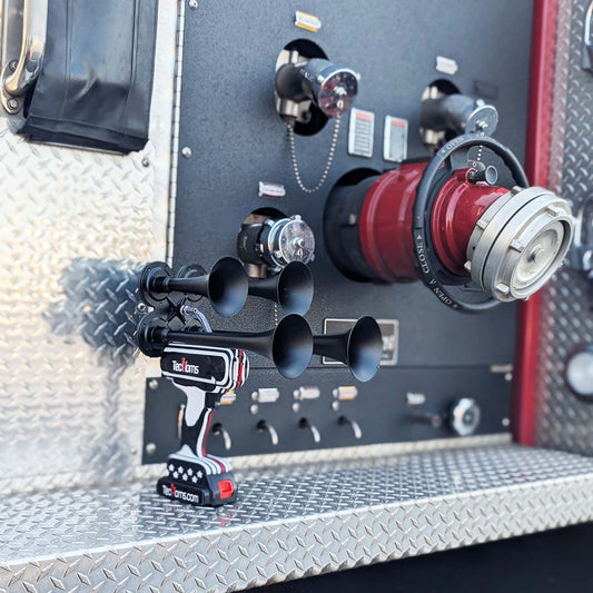 Thin RED Line TecHorns 4-Horn – handheld train horn with 20 V lithium battery, displayed on a fire truck panel with hoses and valves visible, honoring firefighters with its black and white design and Thin RED Line stripe of courage