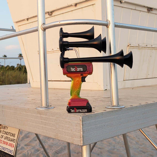 TecHorns Tropical Blaze Candy 5-Horn – 130 dB handheld train horn with 20 V lithium battery, shown on a lifeguard stand with vivid candy fade colors against a coastal backdrop
